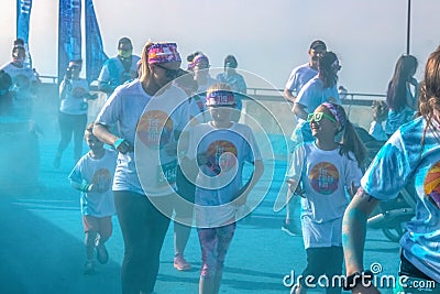 â€ŽApril â€Ž6 â€Ž2019 Tulsa USA Mother and children run laughing through blue powder at color station at Color - holi run - looks Editorial Stock Photo